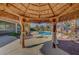 Charming tiki hut offering shade and relaxation with a view of the sparkling pool and palm-filled backyard at 8370 Unicorn St, Las Vegas, NV 89131