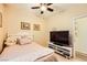 Bright bedroom featuring a ceiling fan, a bed with decorative pillows, and a media center for entertainment at 9557 Cabot Falls Ave, Las Vegas, NV 89149