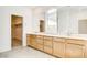 Bathroom featuring double sinks with bright countertops and wood cabinets, with walk-in closet access at 9993 Birch Knoll Ave, Las Vegas, NV 89166