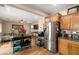 Open kitchen showcasing stainless steel refrigerator, wooden cabinets, and a mobile kitchen island at 10766 La Florentina Ave, Las Vegas, NV 89166