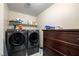 Laundry room featuring dark front load washer and dryer and storage cabinets at 10766 La Florentina Ave, Las Vegas, NV 89166