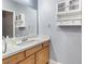 Bright bathroom features a wood vanity, a white countertop, a large mirror, a decorative cabinet, and modern fixtures at 1112 Adobe Creek Ct, North Las Vegas, NV 89084