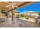 Stylish covered patio with a built-in kitchen, ceiling fans, and views of the landscaped yard at 2776 White Sage Dr, Henderson, NV 89052
