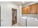 Functional laundry room with washer, dryer, and ample cabinet storage, tile floor and hallway view at 2776 White Sage Dr, Henderson, NV 89052