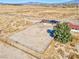 Aerial view of desert property with large fenced yard, home with solar panels, and mountain views in the distance at 2831 Goldrush St, Pahrump, NV 89048