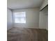 Cozy bedroom with neutral carpet, featuring closet with mirrored doors, and a large window at 3523 Mercury St # G, North Las Vegas, NV 89030