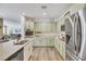 Stylish kitchen showcasing stainless steel appliances, light green cabinetry, and tile flooring at 410 Gracious Way, Henderson, NV 89011