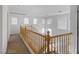 A second-story hallway overlooks an open floorplan, featuring windows, and a wooden bannister at 5081 Pine Mountain Ave, Las Vegas, NV 89139