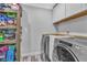 A well-organized laundry room is shown with a washer, dryer, storage shelves and white cabinets at 5700 N Torrey Pines Dr, Las Vegas, NV 89130