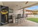 Outdoor kitchen with grill, sink, and refrigerator with barstool seating and tv at 5700 N Torrey Pines Dr, Las Vegas, NV 89130