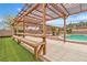 Backyard pergola with wooden bench seating, great for entertaining guests by the pool at 5700 N Torrey Pines Dr, Las Vegas, NV 89130