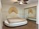 Bright bedroom featuring hardwood floors, a ceiling fan, a unique round bed, and mirrored closet at 6620 Casa Linda Dr, Las Vegas, NV 89103
