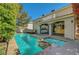 A backyard view of a pool and attached spa, with an outdoor kitchen and a view of the home at 7420 Enchanted Hills Ct, Las Vegas, NV 89129