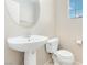 Compact bathroom with a pedestal sink, toilet, mirror, and convenient paper roll holder at 7486 River Dove Ct, Las Vegas, NV 89139