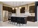 Stylish kitchen with dark wood cabinets, stainless appliances, white countertop island, and modern lighting at 10172 Bismarck Palms Ave, Las Vegas, NV 89166