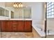Well-lit bathroom with dual sinks, wood cabinets, a soaking tub, and a glass block window at 2229 Suffron Hills Ct, Henderson, NV 89044