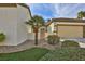 Front exterior showcasing a charming tan home with a two-car garage, palm trees, and desert landscaping at 2229 Suffron Hills Ct, Henderson, NV 89044