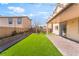 Inviting backyard featuring a covered patio, artificial grass, and brick border, ideal for outdoor enjoyment at 3517 Colby Creek Ave, North Las Vegas, NV 89081