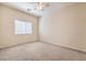 Bright bedroom featuring neutral carpeting, a ceiling fan, and a large window for natural light at 4399 Luciano Ave, Pahrump, NV 89061