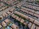 Aerial view showcases a desert neighborhood with homes, community pools, and tree-lined streets at 6148 Whitelion Walk St, Las Vegas, NV 89148