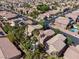 Aerial view of a desert community featuring homes with pools, palm trees, and solar panels at 6148 Whitelion Walk St, Las Vegas, NV 89148