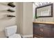 Powder room with dark wood cabinet, vessel sink, black framed mirror and three floating shelves at 6148 Whitelion Walk St, Las Vegas, NV 89148