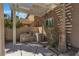 Backyard view of an outdoor kitchen with stone counters and a stainless steel grill, and a dining space under a pergola at 6148 Whitelion Walk St, Las Vegas, NV 89148
