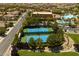 Aerial view of tennis courts with blue playing surfaces, surrounded by trees, grass, and community buildings at 677 Viale Machiavelli Ln, Henderson, NV 89011