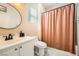 Well-lit bathroom with single vanity, round mirror, and shower with a patterned curtain at 7633 Alexander Hills St, Las Vegas, NV 89139