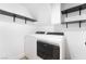 Bright laundry room featuring modern washer and dryer units, accompanied by sleek black shelving for storage at 80 Sea Holly Way, Henderson, NV 89074