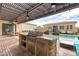 Backyard with outdoor kitchen, stainless steel grill, shaded patio, and pool with inviting lounge seating at 8369 Eagle Estates Ct, Las Vegas, NV 89131