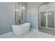 Luxurious bathroom features a standalone tub with chandelier, complemented by modern fixtures and gray marble tile at 8369 Eagle Estates Ct, Las Vegas, NV 89131