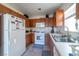 Well-lit kitchen featuring wood cabinetry, tile floors, and white appliances at 9105 Captivating Ave, Las Vegas, NV 89149