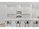 A modern kitchen features white cabinets, stainless appliances, a backsplash and a large island with bar stools at 10165 Canyon Mantle St, Las Vegas, NV 89166