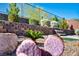 Landscaped backyard with green bushes and plants along a stone retaining wall at 10348 Bressana Dr, Las Vegas, NV 89135