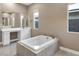Elegant bathroom featuring a soaking tub with tile surround and dual sinks at 10348 Bressana Dr, Las Vegas, NV 89135