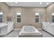 Spa-like primary bathroom boasts a soaking tub, dual vanities, and tiled floors surrounded by natural light at 10348 Bressana Dr, Las Vegas, NV 89135
