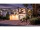 Inviting two-story home with a well-lit three car garage and landscaped front yard at dusk at 2104 Inverness Dr, Henderson, NV 89074