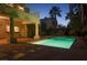 A pristine pool is lit up at dusk, enhanced by a covered patio and meticulously maintained landscaping at 2104 Inverness Dr, Henderson, NV 89074
