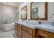 Bright bathroom featuring dual sinks, modern fixtures, wood cabinets, and a freestanding soaking tub at 2729 Echo Mesa Dr, Las Vegas, NV 89134