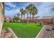 Enjoy the backyard featuring lush artificial turf, palm trees, and desert landscaping at 306 Saint Augustine Ln, Henderson, NV 89014
