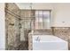 Well-lit bathroom featuring a marble shower, soaking tub, and framed window at 306 Saint Augustine Ln, Henderson, NV 89014
