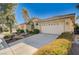 Beige home with wide driveway leading to a two-car garage and desert landscaping, showcasing a serene ambiance at 3663 Coventry Gardens Dr, Las Vegas, NV 89135