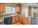 Kitchen area featuring a black dishwasher and wooden cabinets, adjacent to the living area at 3920 Legend Hills St # 202, Las Vegas, NV 89129