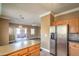 Open concept kitchen with stainless steel refrigerator, light wood cabinets, and view to the living room at 3920 Legend Hills St # 202, Las Vegas, NV 89129