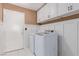 Functional laundry room featuring a washer, dryer, white cabinets, and tiled floor at 5046 Great Abaco St, North Las Vegas, NV 89031