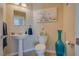 Cozy half bath with pedestal sink, toilet, decorative art, and neutral earth tones at 5640 Coe Estates Ct, Las Vegas, NV 89149
