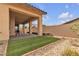 The backyard features a covered patio, artificial turf, decorative stone, and landscaping at 665 Look Lively Ct, Henderson, NV 89011