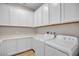 Laundry room with white cabinets, laminate countertops, washer, and dryer at 665 Look Lively Ct, Henderson, NV 89011