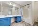 Bright bathroom featuring a double vanity with blue cabinets and a shower over tub at 702 Carlitos Ave, North Las Vegas, NV 89031